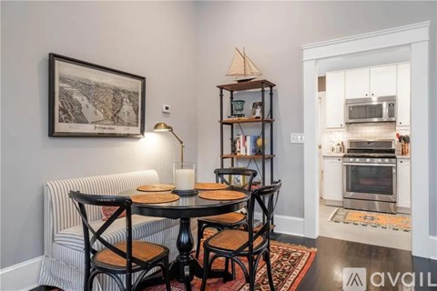 A dining area with a table set for two and a view of a kitchen in the background.