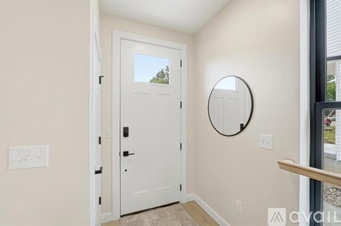 A white door is open in a room with a round mirror on the wall.