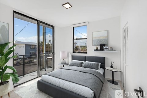 A bedroom with a large bed and a balcony with a view of the outside.