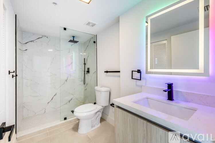 A modern bathroom with a walk-in shower, toilet, and sink.