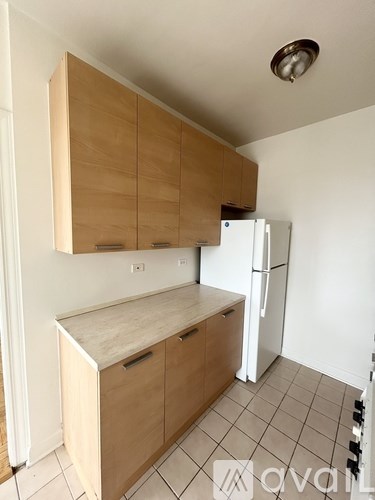 A kitchen with a white fridge and wooden cabinets.
