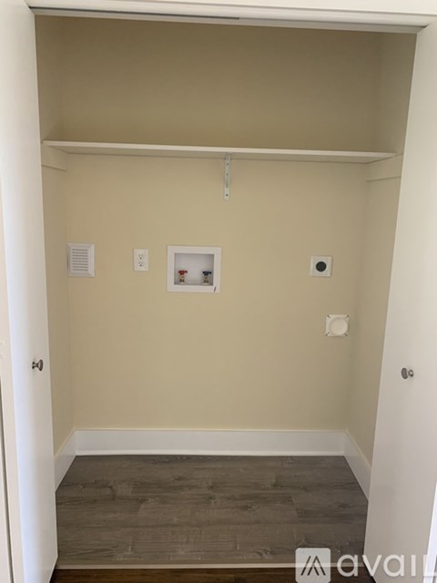 A small, empty room with a door on the left and a shelf on the right.