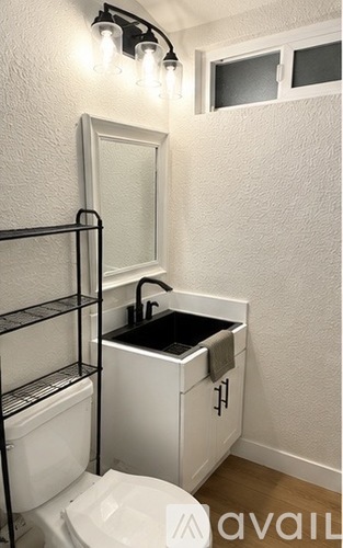 A white bathroom with a toilet, sink, and shelving.