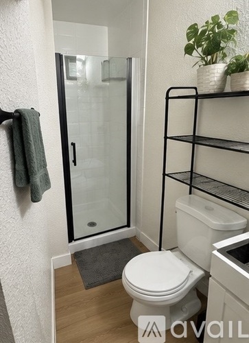 A bathroom with a toilet, sink, and shelves.