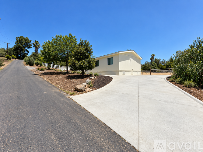 A house with a driveway and trees in the background.
