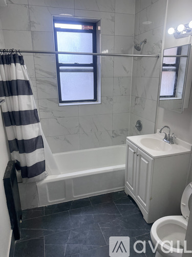 A bathroom with a striped shower curtain and a window.