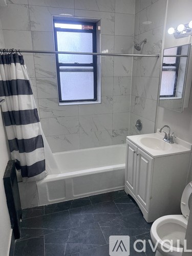 A bathroom with a striped shower curtain and a window.