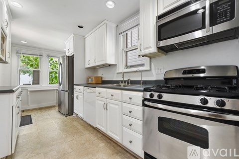 A kitchen with white cabinets and a black stove top oven.