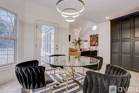 A modern dining room with a glass table and black chairs.