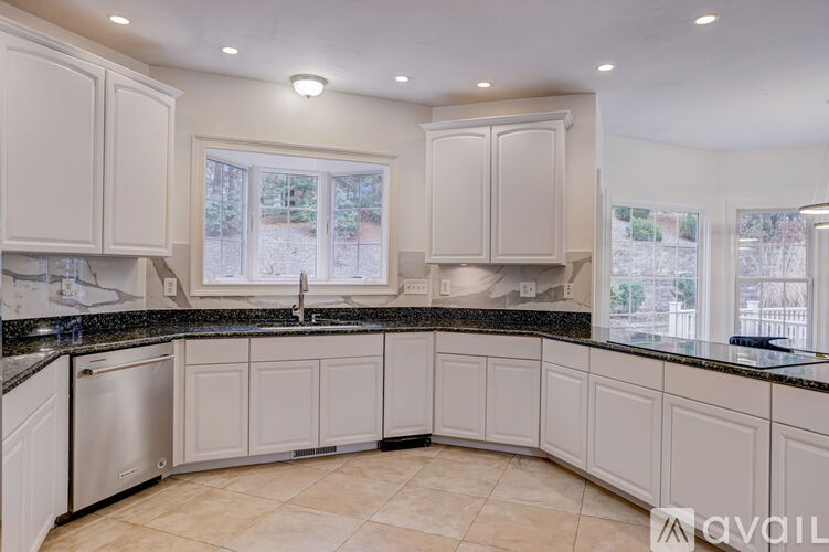 A kitchen with white cabinets and a black countertop.