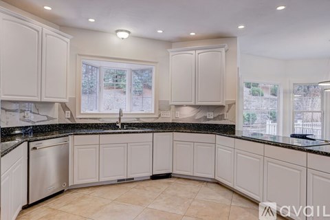 A kitchen with white cabinets and a black countertop.