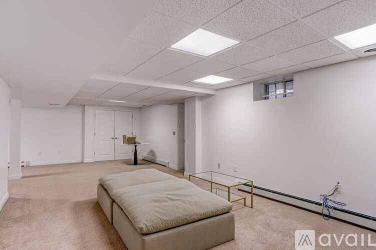 A spacious room with a beige sofa and a glass coffee table.