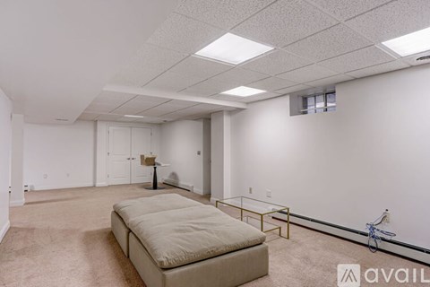 A spacious room with a beige sofa and a glass coffee table.