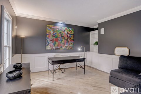 A modern living room with a grey couch and a large abstract painting on the wall.