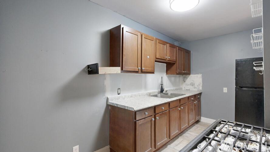 A kitchen with brown cabinets and a black refrigerator.
