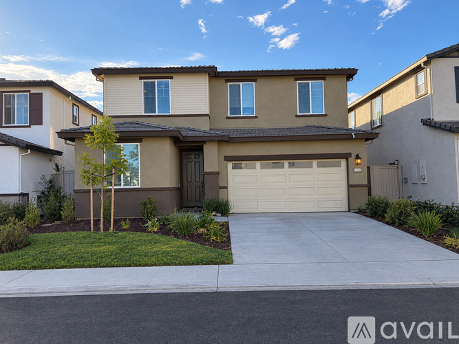 A house with a brown and beige exterior and a white garage door.