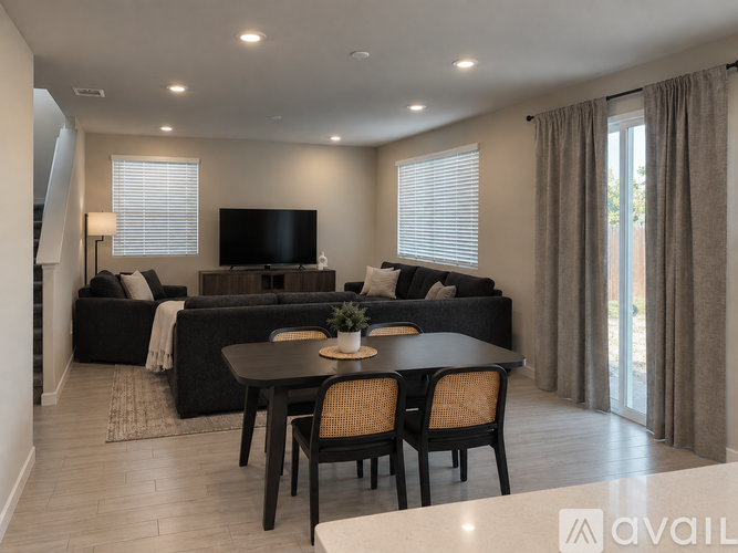 A modern living room with a black sofa, a wooden dining table, and a television.