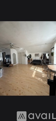 A spacious room with wooden flooring and a ceiling fan.