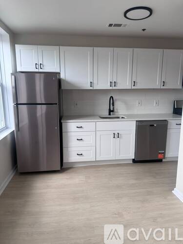 A kitchen with white cabinets and a grey fridge.