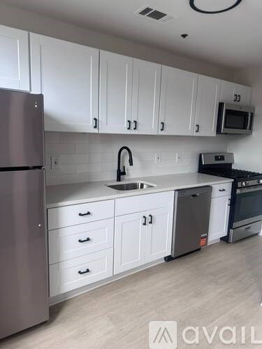 A kitchen with white cabinets and a stainless steel refrigerator.