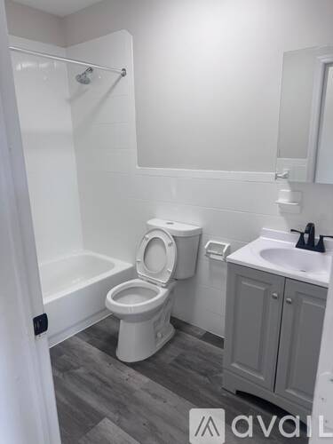 A white toilet in a small bathroom with a white sink and a white cabinet.