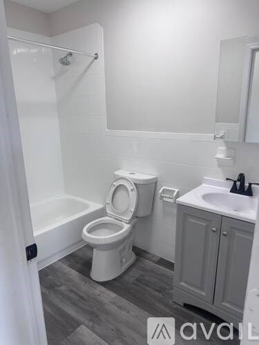 A white toilet in a small bathroom with a white sink and a white cabinet.