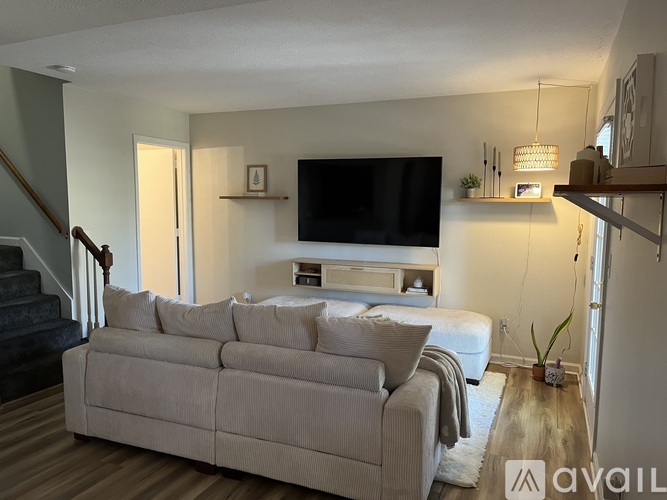 A living room with a large couch and a television on the wall.