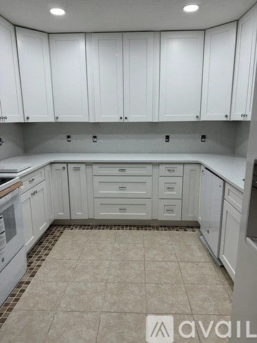 A kitchen with white cabinets and a tiled floor.