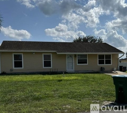 A house with a green trash can in front of it.