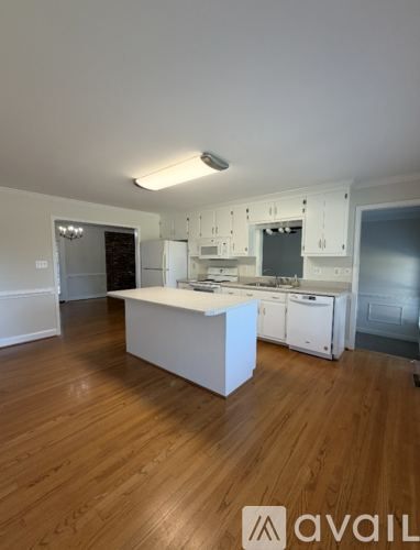 A kitchen with white cabinets and a wooden floor.