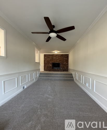 A spacious room with a fireplace and a ceiling fan.