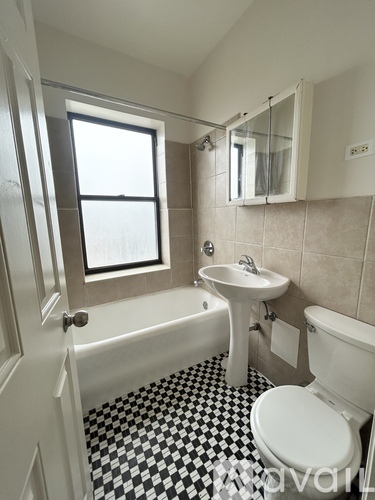 A white toilet sits in a bathroom with a black and white checkered floor.