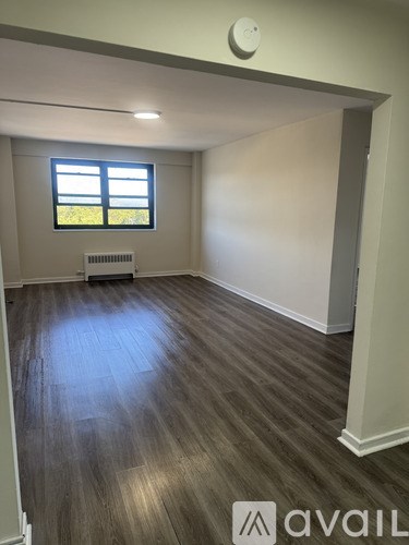 A room with wooden flooring and a window with blinds.