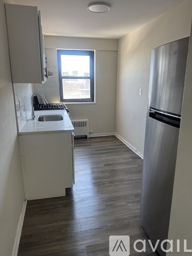 A kitchen with a refrigerator, sink, and window.