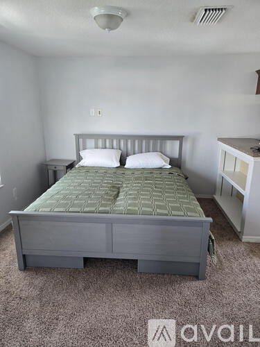 A bed with a green patterned mattress pad sits in a room with white walls.