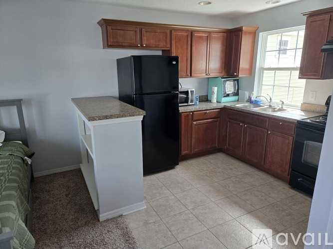 A kitchen with a black refrigerator and brown cabinets.