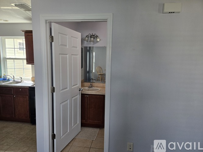 A bathroom with a white door and a mirror above the sink.