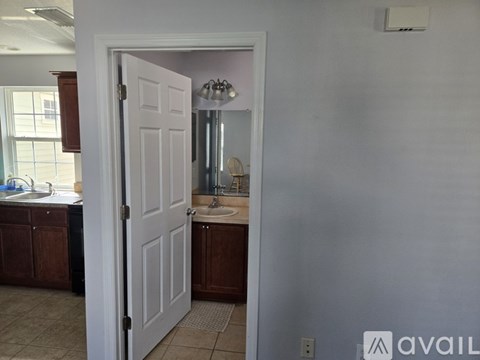A bathroom with a white door and a mirror above the sink.