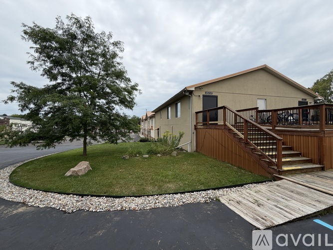 A house with a brown deck and a tree in front of it.