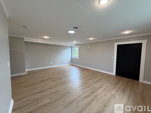 A spacious room with wooden flooring and a large window.