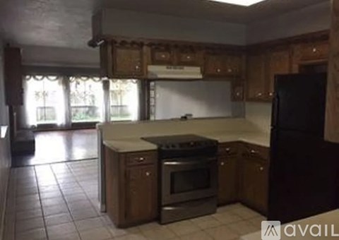 A kitchen with wooden cabinets and a black refrigerator.