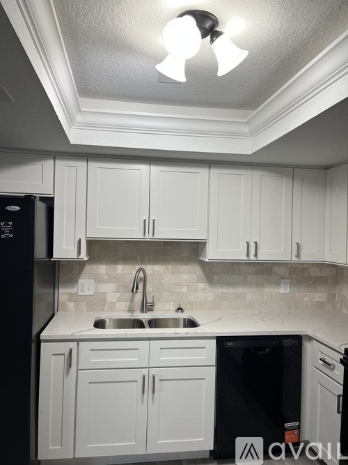 A kitchen with white cabinets and a black fridge.
