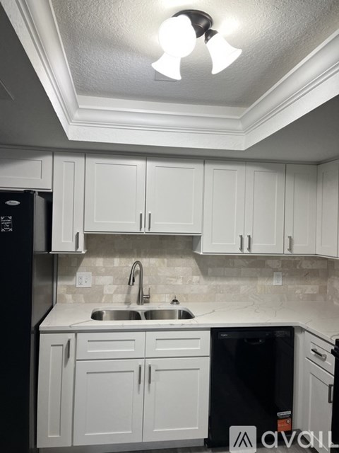 A kitchen with white cabinets and a black fridge.