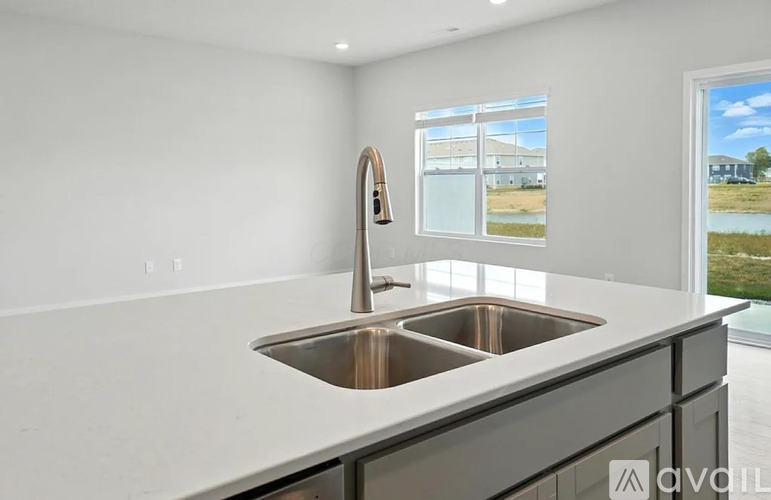 A modern kitchen with a double sink and a window showing a view of a building and a field.