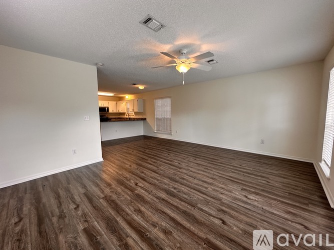 A spacious room with wooden flooring and a ceiling fan.