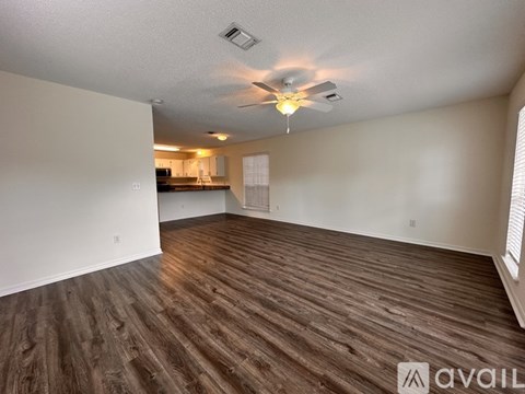 A spacious room with wooden flooring and a ceiling fan.