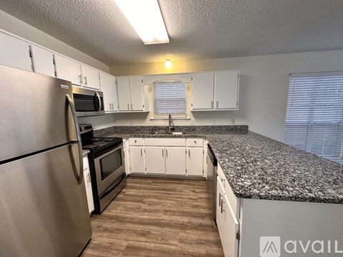 A kitchen with a granite countertop and stainless steel appliances.
