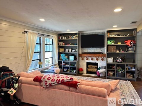 A living room with a pink couch and a fireplace.