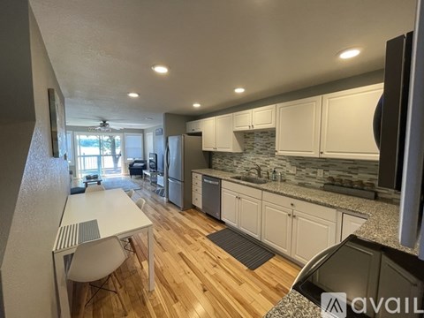A kitchen with a table and chairs in the foreground and a counter top with a sink in the background.
