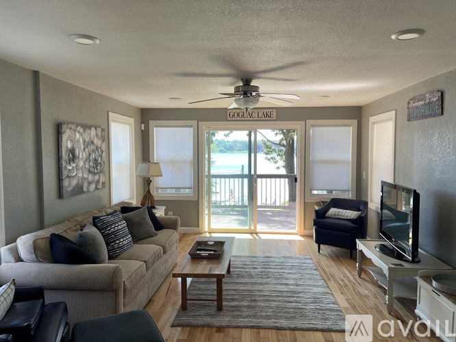 A living room with a couch, a coffee table, a television, and a fan.
